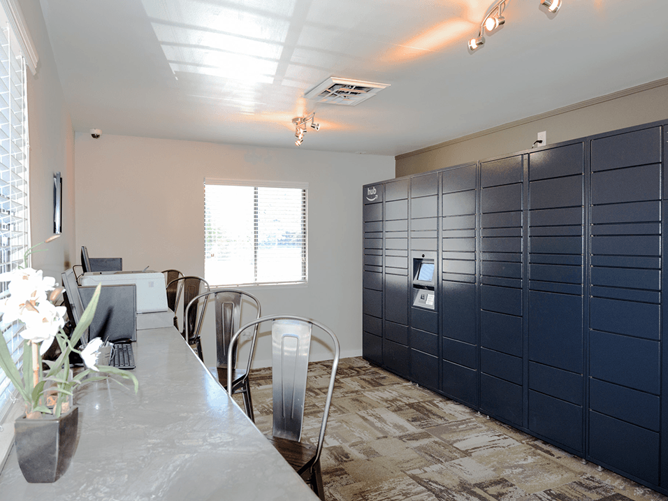 a long table with chairs in a room with lockers and a window
