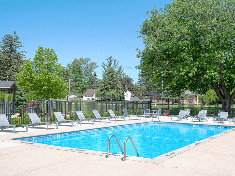 a swimming pool with chaise lounge chairs and trees in the background