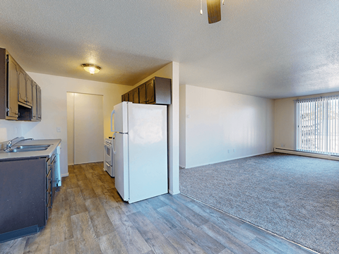 A kitchen with a white refrigerator and wooden floors.