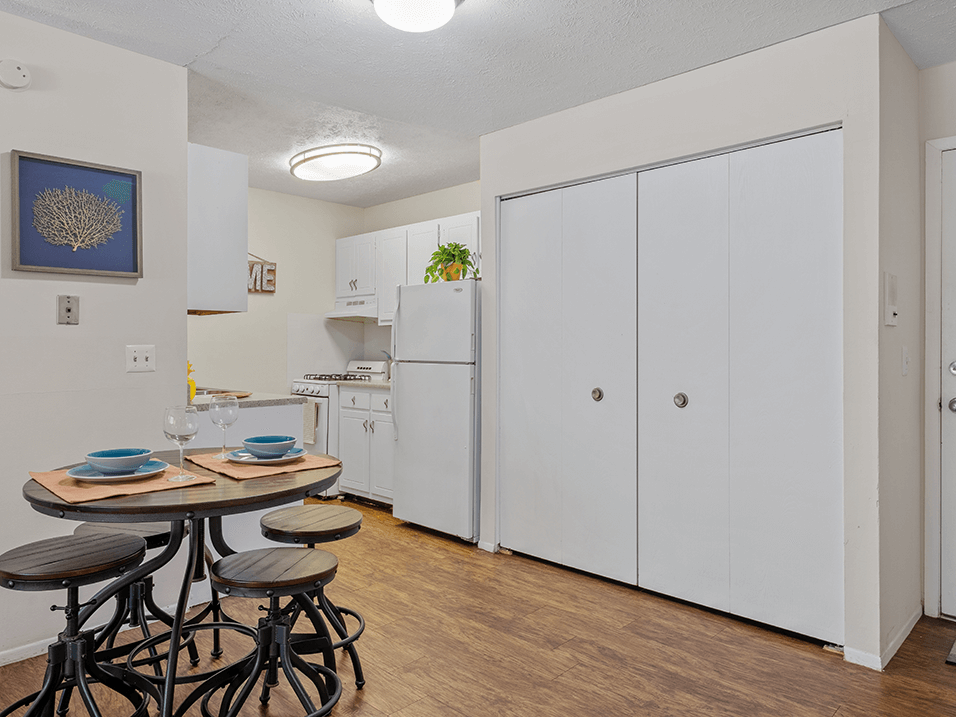 a kitchen with white cabinets and a small table with three stools