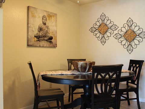 A dining room with a table and chairs and a Buddha picture on the wall.