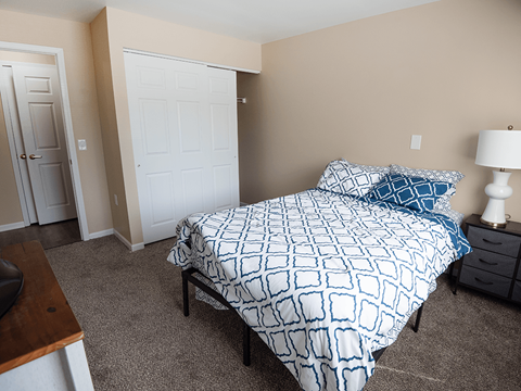 A bedroom with a bed, nightstand, and two doors.
