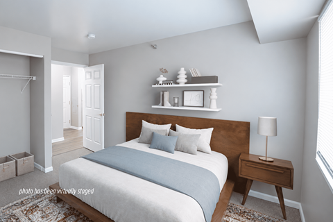 A bedroom with a bed, nightstand, and a window.