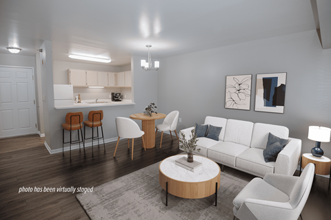A living room with a white couch, a coffee table, and a dining table with chairs.