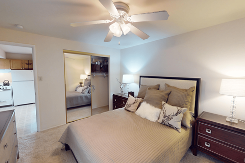 A bedroom with a large bed and a ceiling fan.