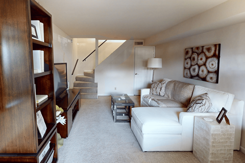 A living room with a white couch and a wooden bookcase.