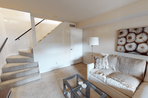 A living room with a couch, coffee table, and stairs.