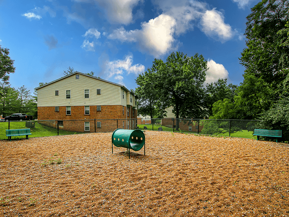 a fenced in dog park with a house in the background