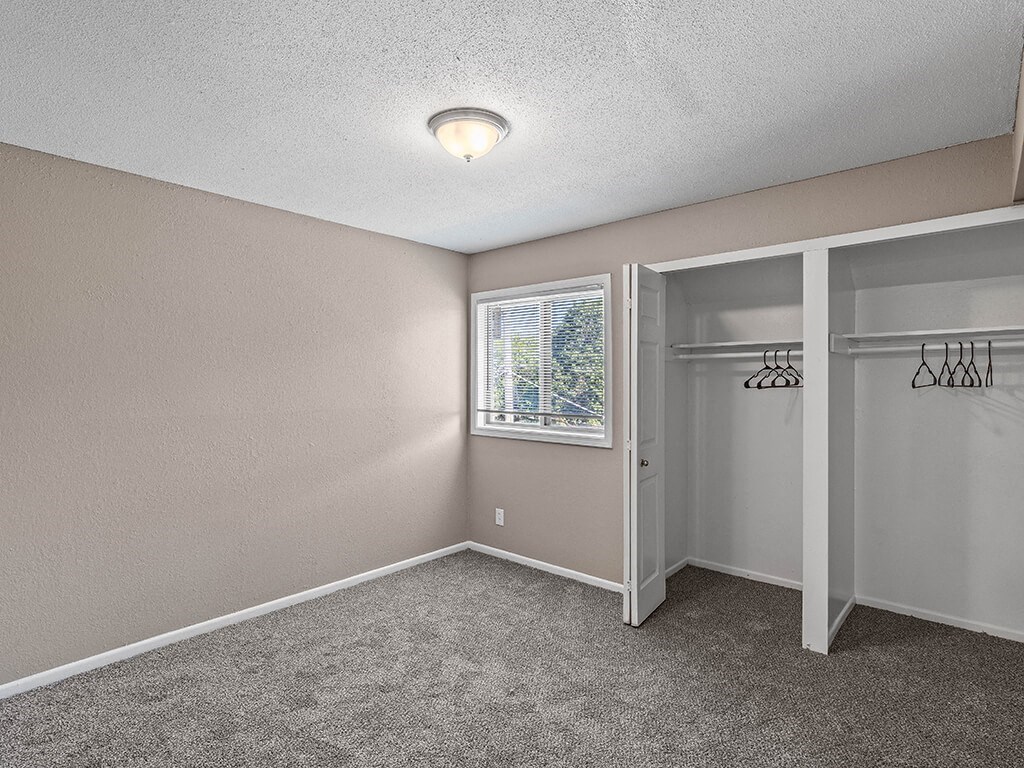 an empty bedroom with a closet and a window