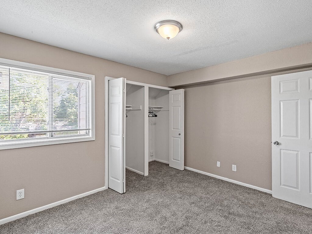 an empty bedroom with a window and a closet
