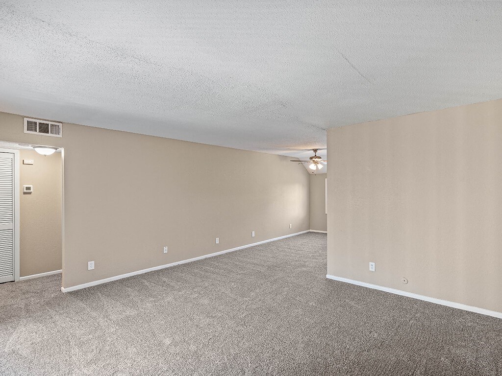 an empty living room with carpet and a door to a closet