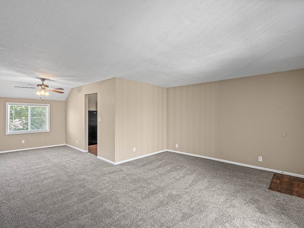 an empty living room with carpet and a ceiling fan
