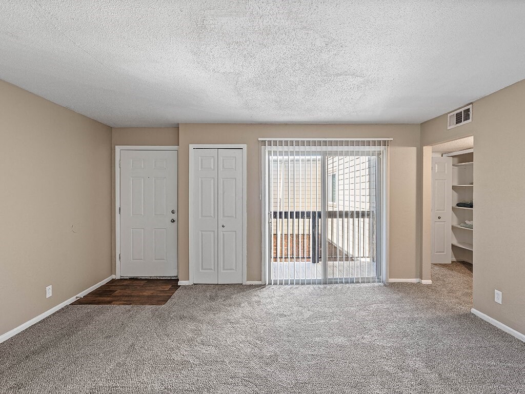 an empty living room with a door to a balcony