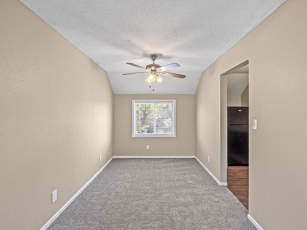 an empty room with a ceiling fan and a window