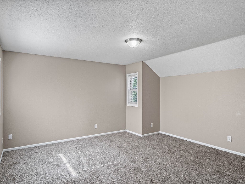 an empty living room with carpet and a light on the ceiling