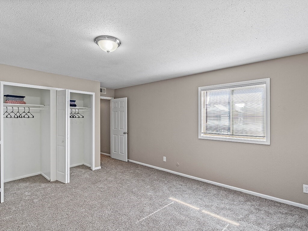 an empty room with a window and a closet