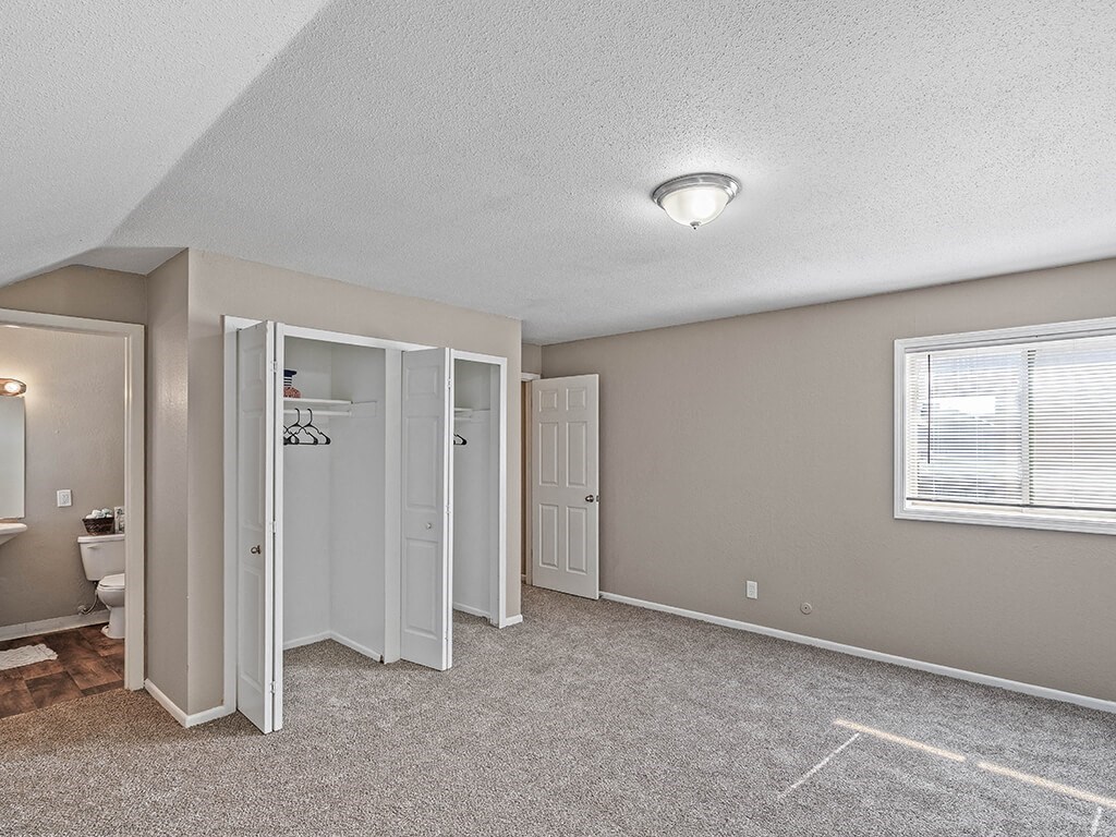 an empty bedroom with an attached bathroom and a closet