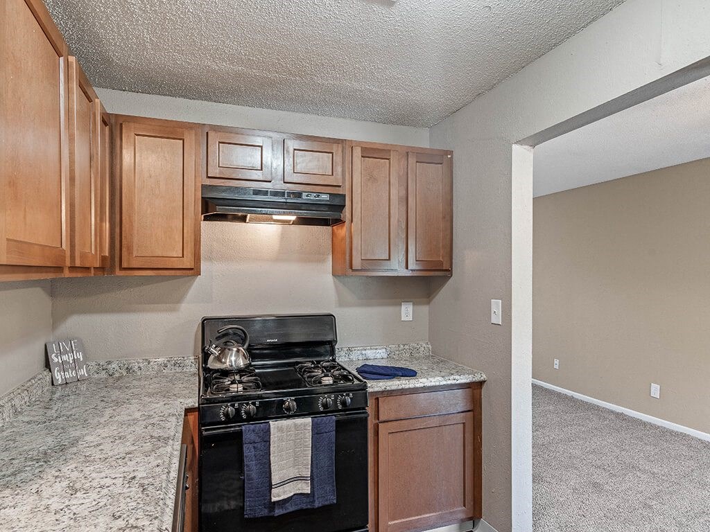 an empty kitchen with wood cabinets and a black stove