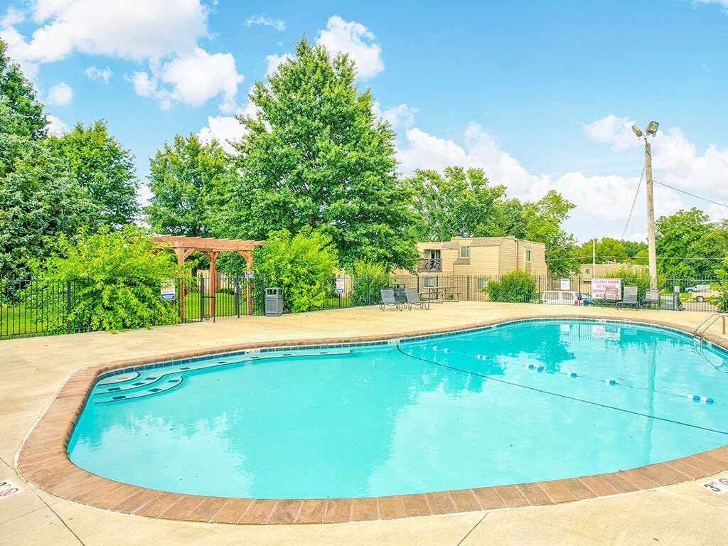a swimming pool with trees and a building in the background
