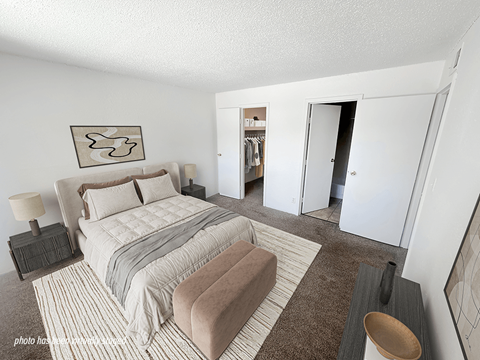 A bedroom with a large bed and a wardrobe in the background.