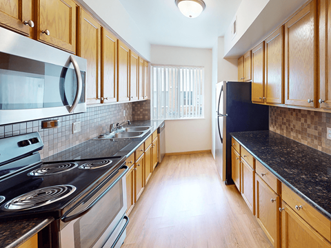 A kitchen with wooden cabinets and a black counter top.