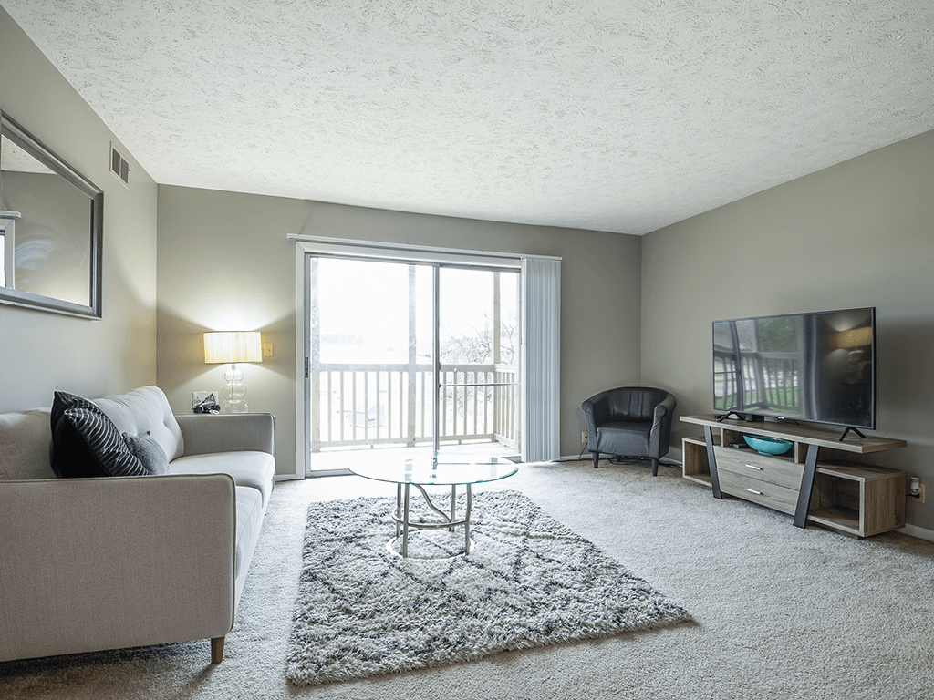 a living room with a couch and a tv and a balcony