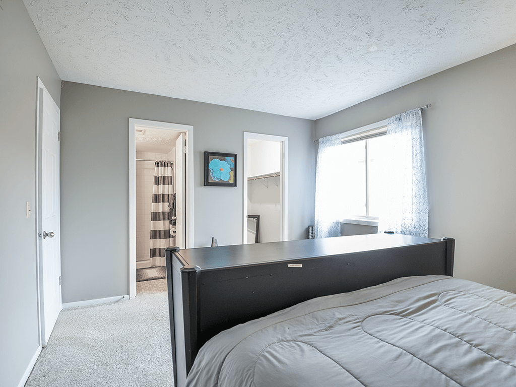 an empty bedroom with a bed and a bathroom