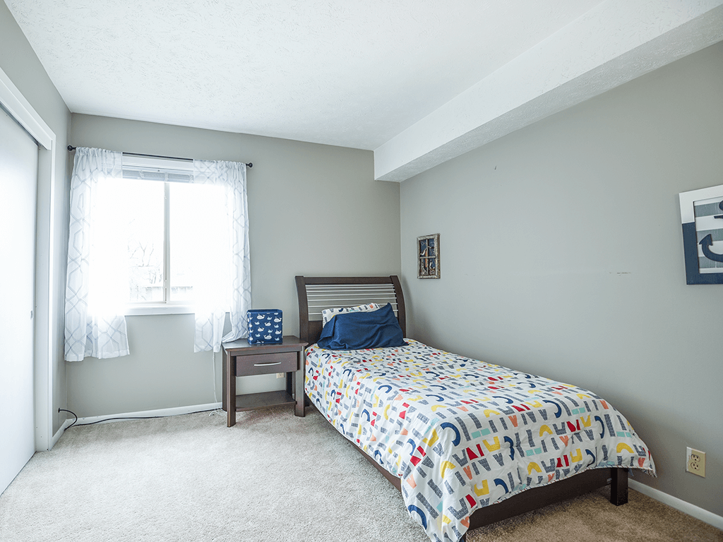 a bedroom with a bed and a chair and a window