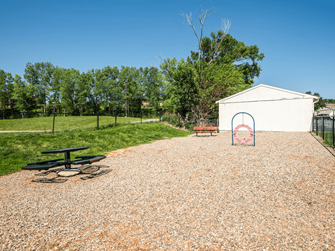 a gravel area with a picnic table and a bench in front of a white building