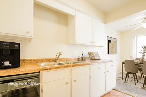 A kitchen with white cabinets and a black microwave.