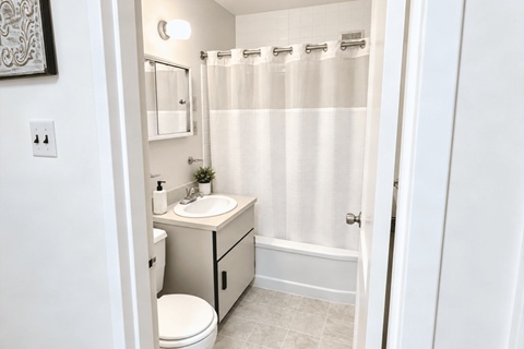A white bathroom with a toilet, sink, and shower.