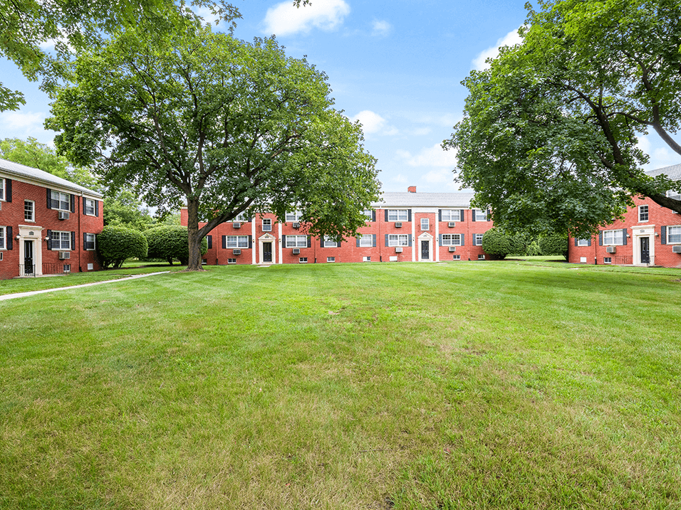 a large green lawn in front of brick apartment building