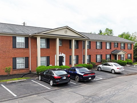 A black car is parked in front of a brick building.