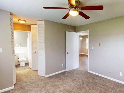 A room with a ceiling fan and carpeted floor.
