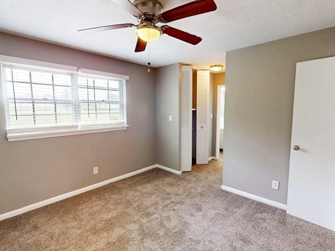 A room with a ceiling fan and carpeted floor.