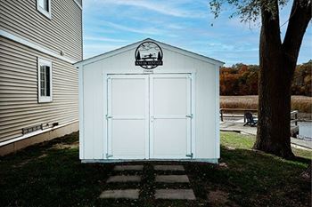 A white shed with a black logo on the door.