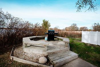 A wooden table with a black box on top is situated in a garden.