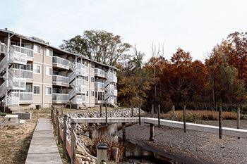 Apartment building with a walkway and bridge over a pond.