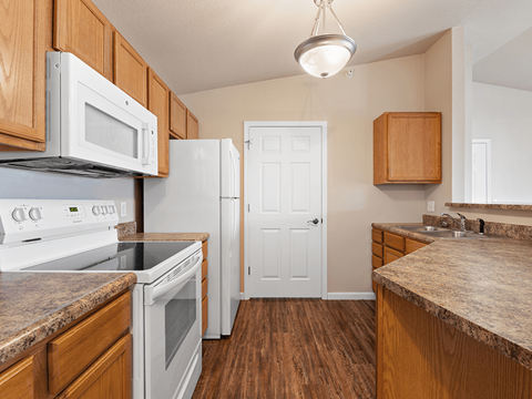 A kitchen with white appliances and wooden cabinets.