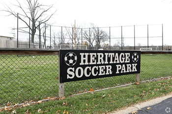 a sign for the heritage soccer park in front of a fence