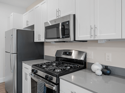 A black refrigerator and stove in a kitchen with white cabinets.