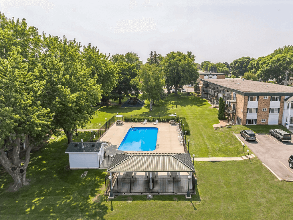 an aerial view of a swimming pool in the middle of a yard with a building