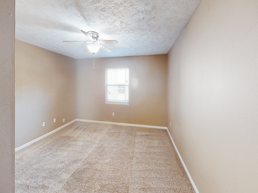 A room with a ceiling fan and carpeted floor.