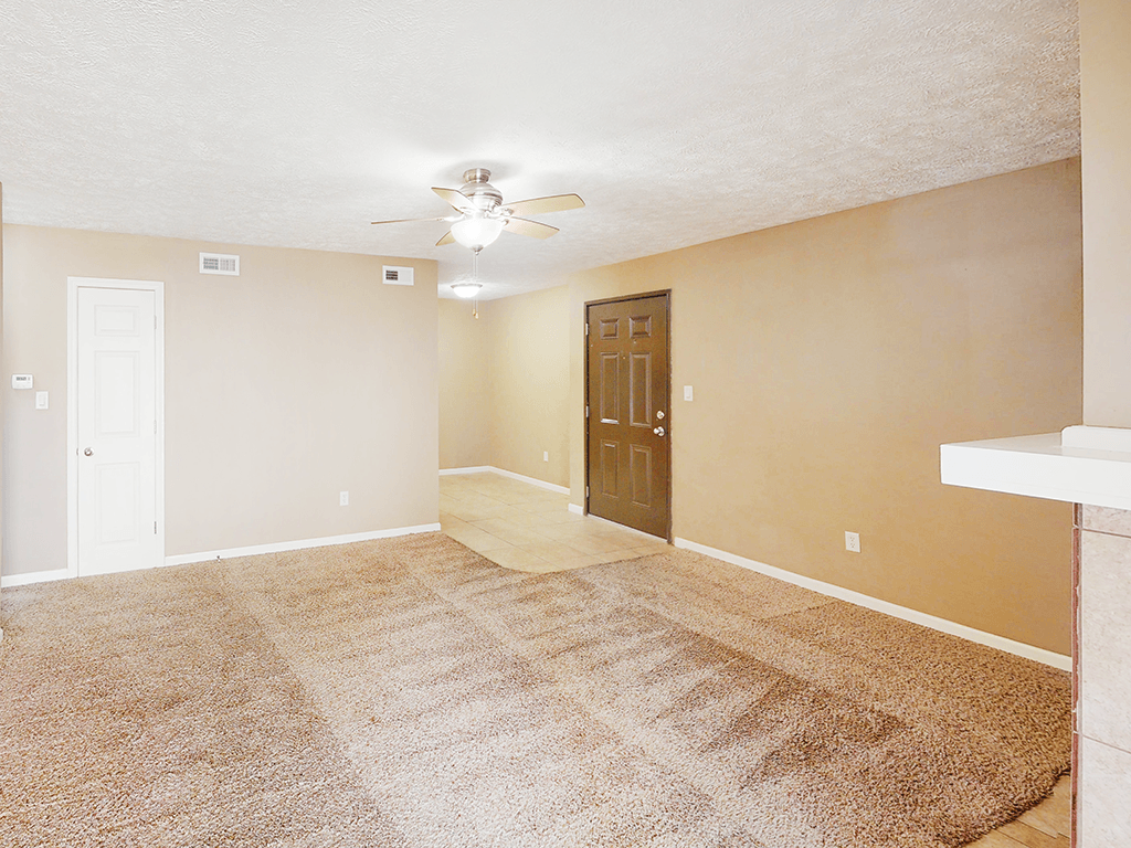 A room with a carpeted floor and a ceiling fan.