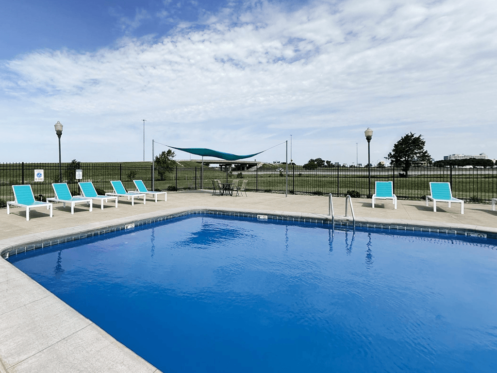 A swimming pool with blue water and white lounge chairs.