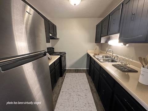 A kitchen with black cabinets and a stainless steel refrigerator.