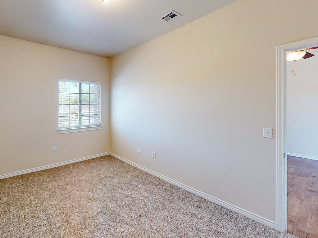 an empty living room with a window and carpet