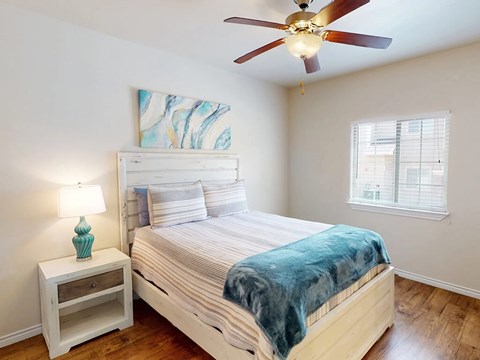 A bedroom with a bed, a nightstand, and a ceiling fan.