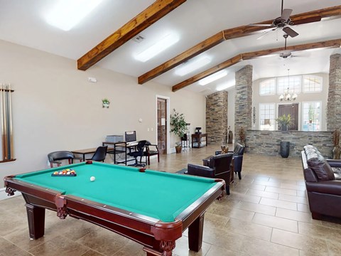 A pool table is in the middle of a room with a couch and chairs.