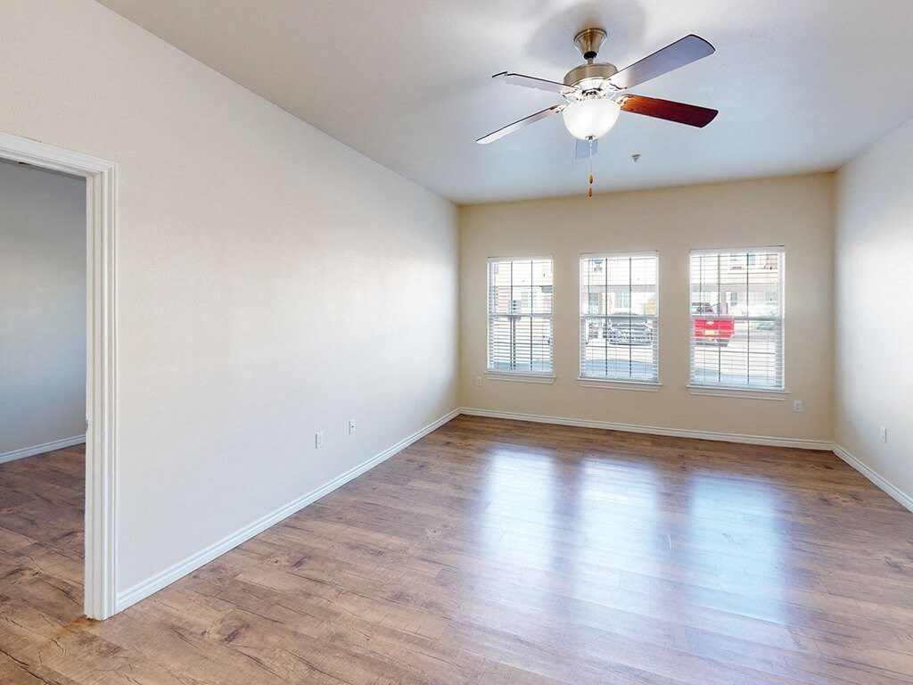 an empty living room with a ceiling fan and a window